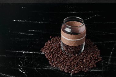Siyah arka planda kahve çekirdekleri ve cam kavanozda. Yüksek kalite fotoğraf
