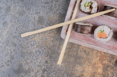Tahtada yemek çubukları olan lezzetli suşi seti.