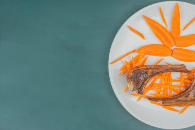 Beyaz tabakta kuzu pirzolası ve havuç dilimleri. Yüksek kalite fotoğraf