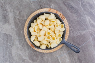 Tahta bir tepside siyah bir tavada pişirilmiş makarna. Yüksek kalite fotoğraf