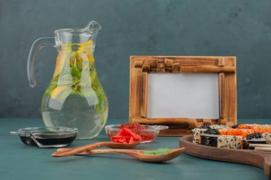 Mavi yüzeyde karışık suşi tabağı, limonata ve resim çerçevesi. Yüksek kalite fotoğraf