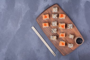 Suşi seti. Philadelphia ve Alaska yemek çubuklarıyla ahşap tabakta yuvarlanıyor. Yüksek kalite fotoğraf