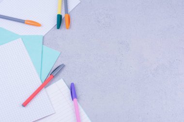 Boş kağıtlar ve gri arka planda izole edilmiş çok renkli kalemler. Yüksek kalite fotoğraf