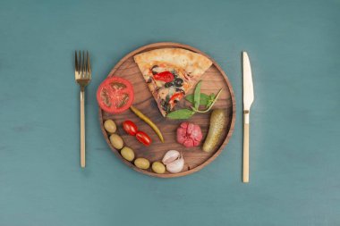 Bir dilim pizza, sebze turşusu ve ahşap tabakta çatal bıçak takımı. Yüksek kalite fotoğraf