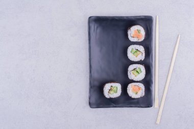 Sake maki somon ve avokado ile seramik siyah tabakta yuvarlanır. Yüksek kalite fotoğraf