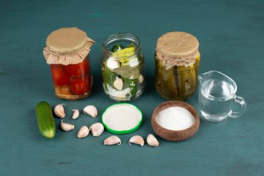 Cam kavanozda sebze turşusu ve mavi arka planda tuz kasesi ve taze sarımsak. Yüksek kalite fotoğraf