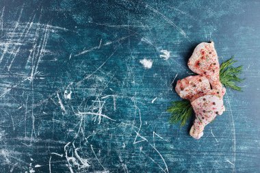 Mavi arka planda baharatlı ve otlu çiğ tavuk bacağı. Yüksek kalite fotoğraf