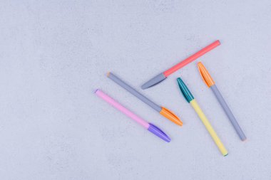 Gri arkaplanda beş tane çok renkli jel kalem var. Yüksek kalite fotoğraf