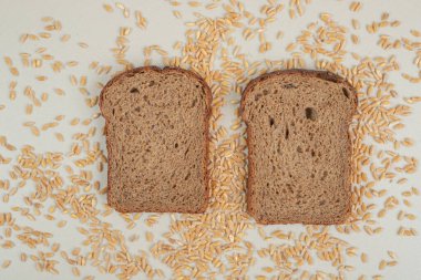 Beyaz zemin üzerinde yulaf taneleri olan dilimlenmiş taze kahverengi ekmek. Yüksek kalite fotoğraf