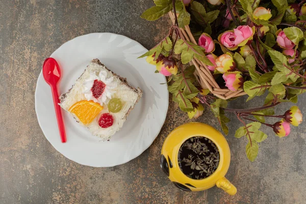 An emoji mug with sweet cake and spoon on marble background