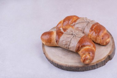 Kruvasanlar, gri arka plandaki ahşap bir tabakta izole edilmiş. Yüksek kalite fotoğraf