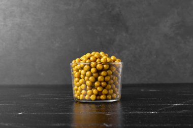 Siyah arka planda cam bir fincanda yeşil bezelyeler. Yüksek kalite fotoğraf