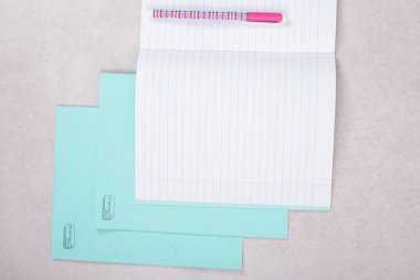 Beyaz arka planda pembe kalemli mavi beyaz kağıtlar.