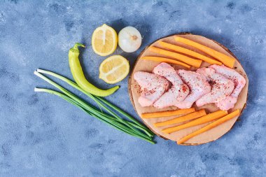 Mavi arka planda tahta bir tahtada sebzeli tavuk kanadı. Yüksek kalite fotoğraf