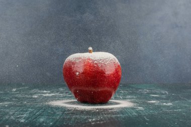 Mavi arka planda pudra ile süslenmiş kırmızı elma. Yüksek kalite fotoğraf