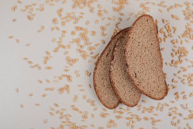 Beyaz zemin üzerinde yulaf taneleri olan dilimlenmiş taze kahverengi ekmek. Yüksek kalite fotoğraf