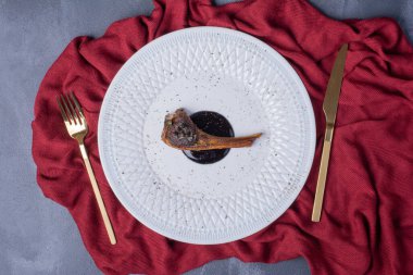 Kırmızı masa örtüsü ve mavi arka planda çatal bıçak takımı ile beyaz tabakta kuzu pirzolası. Yüksek kalite fotoğraf