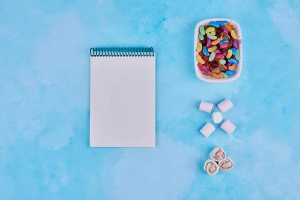 Tazón Caramelos Malvaviscos Delicias Cuaderno Sobre Fondo Azul Foto Alta — Foto de Stock