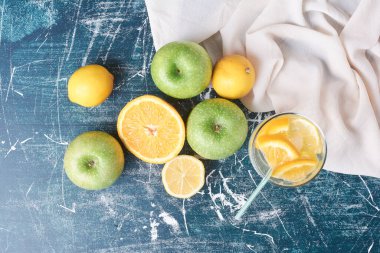 Mavi arka planda bir bardak içkili limon ve elma. Yüksek kalite fotoğraf