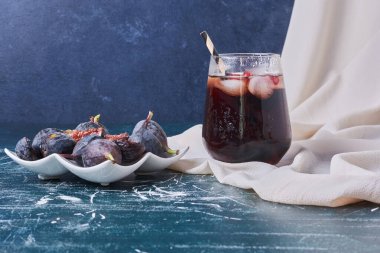 Mavi arka planda mor incirli bir bardak meyve suyu. Yüksek kalite fotoğraf