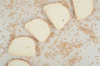 Beyaz zemin üzerinde yulaf taneleri olan dilimlenmiş taze beyaz ekmek. Yüksek kalite fotoğraf
