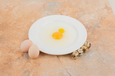 Beyaz tabakta çiğ yumurta ve birkaç bıldırcın yumurtası. Yüksek kalite fotoğraf