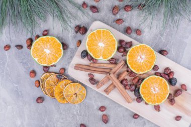 Kuru kalçalı portakal dilimleri ve ahşap tabakta tarçın çubukları. Yüksek kalite fotoğraf