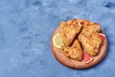 Mavi arka planda ahşap bir tahtada kızarmış tavuk kanadı. Yüksek kalite fotoğraf