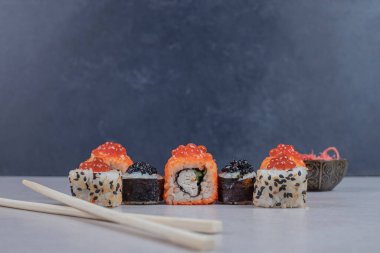 Kırmızı havyar ve çubuklarla süslenmiş çeşitli suşi ruloları. Yüksek kalite fotoğraf
