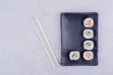 Sake maki somon ve avokado ile siyah seramik tabakta yuvarlanır. Yüksek kalite fotoğraf