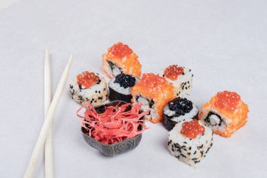 Beyaz arka planda, yemek çubukları ve turşulu zencefilli klasik suşi ruloları. Yüksek kalite fotoğraf