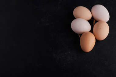 Ortadaki yumurtalar siyah arkaplanda, üst görünümde. Yüksek kalite fotoğraf