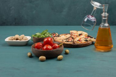 Bir dilim pizza, domates turşusu, zeytin ve mavi masada cam bir şişe. Yüksek kalite fotoğraf