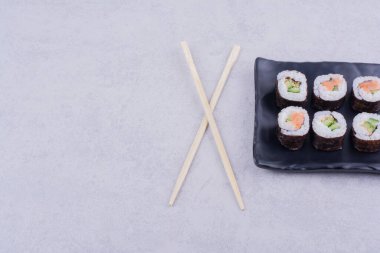 Sake maki somon ve avokado ile seramik siyah tabakta yuvarlanır. Yüksek kalite fotoğraf
