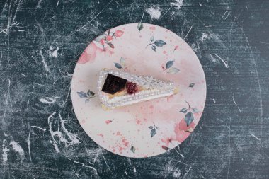 Renkli tabakta incilerle süslenmiş bir dilim peynirli kek. Yüksek kalite fotoğraf