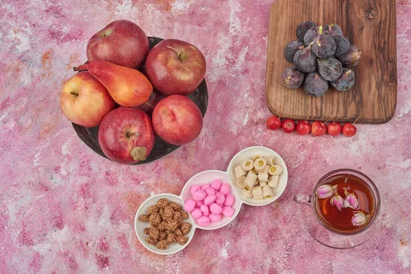 Purple figs on a wooden board with tea and candies around. High quality photo