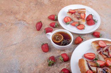 Bir fincan çayla birlikte beyaz tabakta çikolata soslu çilekli turta. Yüksek kalite fotoğraf