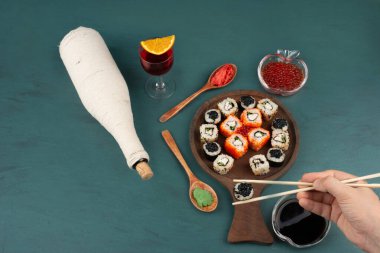 Kadın eli yemek çubuğu ve bir bardak şarapla suşi yiyordu. Yüksek kalite fotoğraf