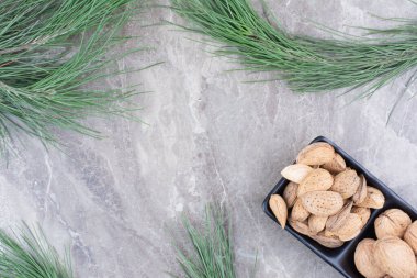 Mermer zemin üzerinde badem ve ceviz dolu siyah bir tabak. Yüksek kalite fotoğraf