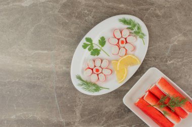 Yeşillikli yengeç çubukları ve beyaz tabakta limon. Yüksek kalite fotoğraf