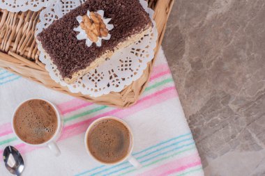 Mermer zemin üzerinde tatlı kek olan iki fincan kahve. 