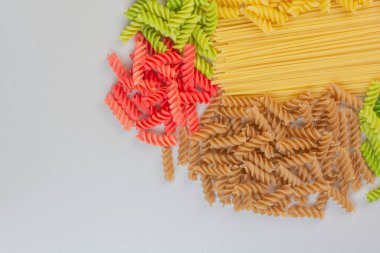 Beyaz yüzeyde pişmemiş renkli spiral makarna ve spagetti. Yüksek kalite fotoğraf