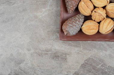 Ceviz şeklinde kurabiyeler ve siyah tabakta kozalaklar. Yüksek kalite fotoğraf