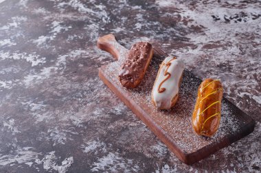 Tahta bir tahtanın üstünde beyaz ve karamel kremalı ekler. Yüksek kalite fotoğraf