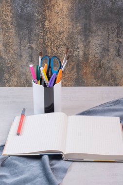 Kalem tutacağında makas, fırça ve kalemler ve açık defter. Yüksek kalite fotoğraf