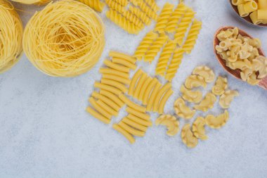  Beyaz arka planda çeşitli makarna şekilleri ve kaşıklar. Yüksek kalite fotoğraf