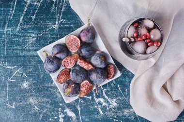 Mor incirler ve mavi arka planda bir bardak içki. Yüksek kalite fotoğraf