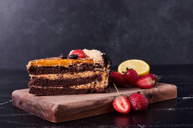 Tahtada krema ve çilekle süslenmiş çikolatalı pasta. Yüksek kalite fotoğraf