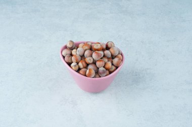 Mermer arka planda fındık dolu pembe bir tabak. Yüksek kalite fotoğraf