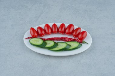 Beyaz tabak salatalık, domates vişneli ve biberli. Yüksek kalite fotoğraf